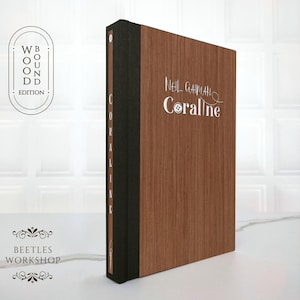 Special edition of Coraline by Neil Gaiman featuring a dark brown handcrafted wooden cover with silver embossed title and decorative details
