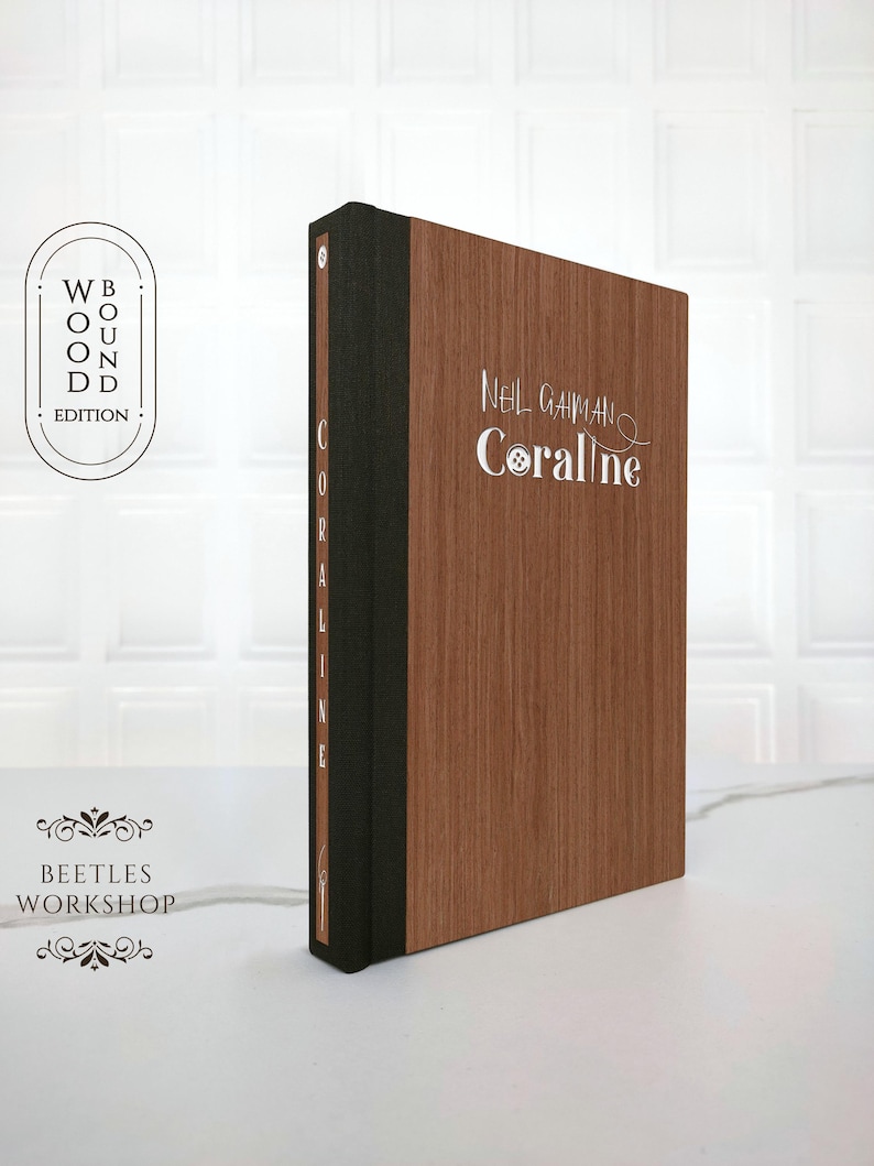 Special edition of Coraline by Neil Gaiman featuring a dark brown handcrafted wooden cover with silver embossed title and decorative details