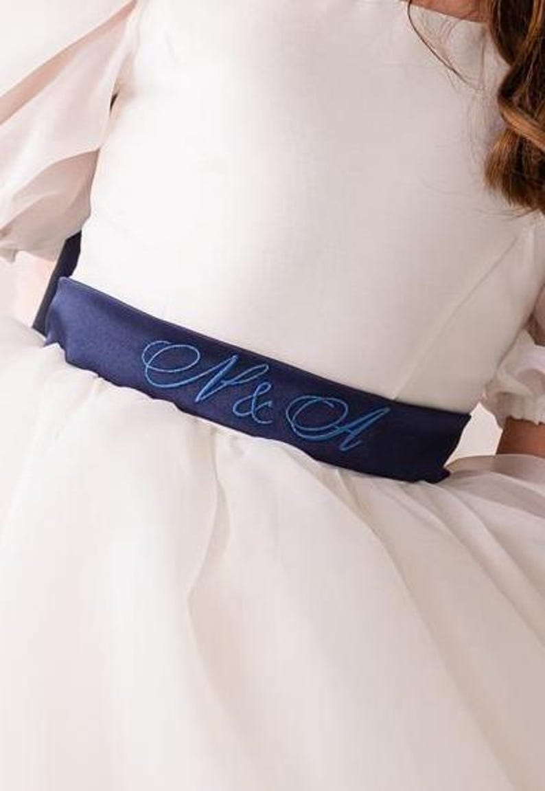 personalized first communion dress, custom flower girl dress, embroidered belt dress, first holy communion outfit, heirloom dress for girls, embroidered sash dress, ivory dress with monogram, white dress with big bow, special occasion dress girl, birthday dress with embroidered sash, wedding dress for young girls, flower girl dress with ribbon bow, baptism dress with embroidered belt