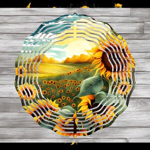 May include: A circular metal wind chime with a design of a field of sunflowers in front of a mountain range. The background is a blue sky with white clouds. The wind chime is made of metal and has a silver finish.