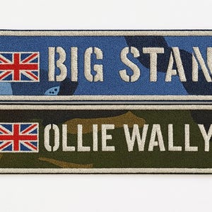 May include: Two rectangular embroidered patches with a border. The top patch features a blue camouflage pattern with the text BIG STAN and a Union Jack. The bottom patch features a green camouflage pattern with the text OLLIE WALLY and a Union Jack.