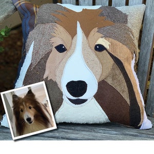May include: A decorative pillow featuring a dog's face, crafted from various fabric textures and colors. The dog's face is primarily brown, white, and black, with a detailed patchwork design. A framed photo of the dog is in the lower left corner.