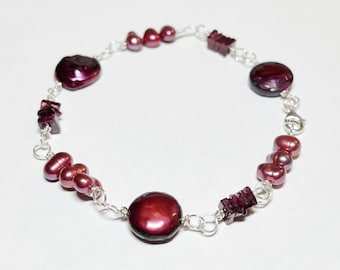 May include: A silver chain bracelet with burgundy pearls and garnet stones.