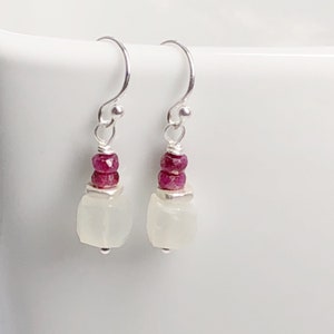 May include: Silver dangle earrings with a white moonstone and pink ruby beads.