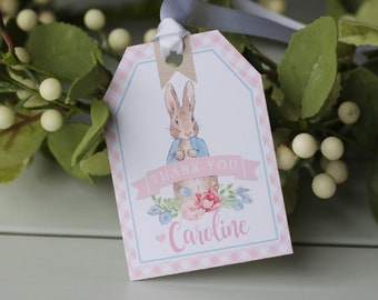 May include: A pink and blue thank you tag with a white background featuring a cartoon rabbit in a blue jacket. The tag has a pink gingham border and the text "Thank You" and "Caroline" in blue.