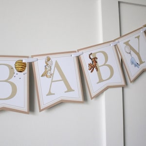 May include: A Winnie the Pooh themed baby shower banner with the word "BABY" in white letters on a brown background. Each letter has a different Winnie the Pooh character or object on it.