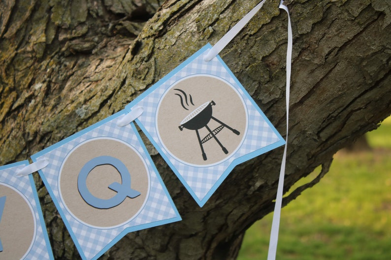May include: A blue and white gingham banner with the letter Q and a black and white illustration of a grill with smoke coming from it.