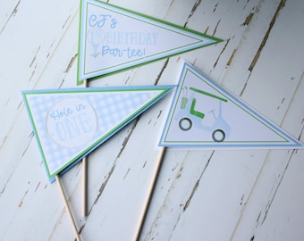 May include: Three blue and green pennant flags with golf-themed designs. The flags read "CJ's 1st Birthday Par-tee!", "Hole in One", and a golf cart.