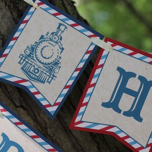 May include: A blue and red striped banner with the letters "H" and a vintage train engine illustration. The banner is made of paper and has a rustic look.