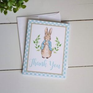 May include: A blue and white checkered thank you card with a watercolor illustration of Peter Rabbit in a blue jacket. The card says "Thank You" in cursive.
