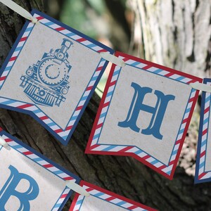 May include: A red, white, and blue banner with the words "Happy" and a train engine illustration. The banner is made of paper and has a vintage look.