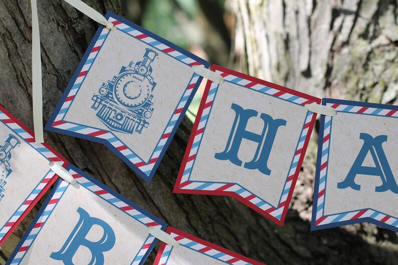 May include: A red, white, and blue banner with the words "Happy" and a train engine illustration. The banner is made of paper and has a vintage look.
