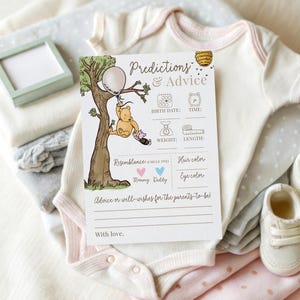 K&ouml;nnte beinhalten: Eine Babyparty-Spielkarte mit dem Text "Predictions & Advice" und einer Winnie-Puuh-Illustration. Die Karte ist von gefalteter Babykleidung in Wei&szlig;, Rosa und Grau sowie einem Paar Babyschuhe umgeben.