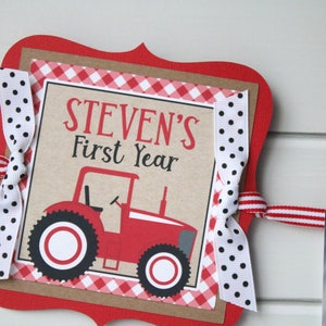 May include: Red and white banner with a red tractor and the text "STEVEN'S First Year" on a brown background. The banner is decorated with red and white gingham ribbon and black and white polka dot ribbon.