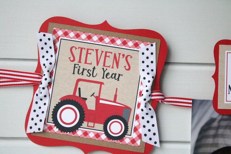 May include: Red and white banner with a red tractor and the text "STEVEN'S First Year" on a brown background. The banner is decorated with red and white gingham ribbon and black and white polka dot ribbon.