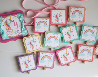 May include: A unicorn-themed birthday banner with a pink, gold, and white color scheme. The banner features a large pink square with a unicorn, the number 4, and the name Chloe. There are also smaller square cards with unicorns, rainbows, and stars.