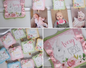 May include: A baby's first year photo banner with a bunny and floral design. The banner includes individual photo holders for each month, with the text "Avery's First Year" and "Just Born". The color scheme is pink, green, and white.