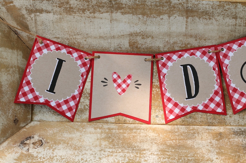 May include: A red and white gingham banner with the words "I DO" in black letters. The banner is strung with twine and has a heart-shaped cutout in the middle.