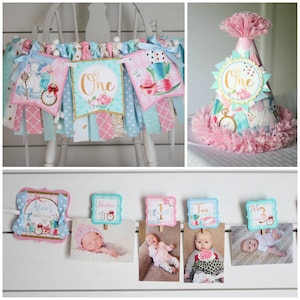 May include: Alice in Wonderland themed first birthday party decorations. A banner with a pink and blue color scheme features images of Alice, the Mad Hatter, and the Queen of Hearts. The banner says "One" in gold letters. A pink and blue party hat with a gold crown and the word "One" is also included. A photo collage with images of a baby at different ages is shown with a pink and blue Alice in Wonderland theme.