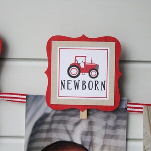 May include: Red and white banner with a red tractor and the word "NEWBORN" on a brown background. The banner is decorated with red and white ribbon.