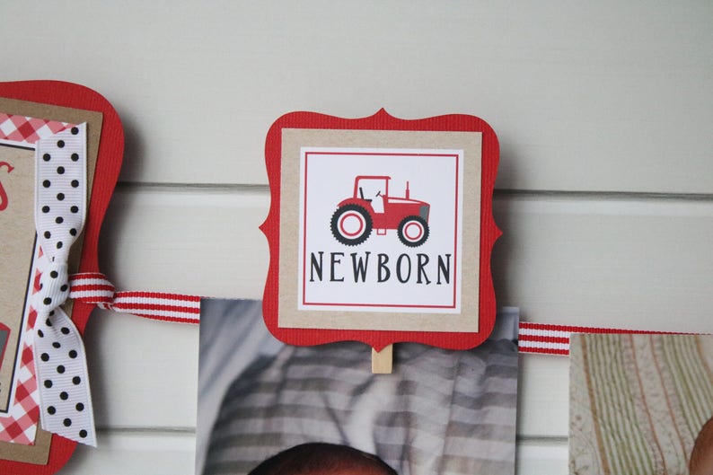 May include: Red and white banner with a red tractor and the word "NEWBORN" on a brown background. The banner is decorated with red and white ribbon.
