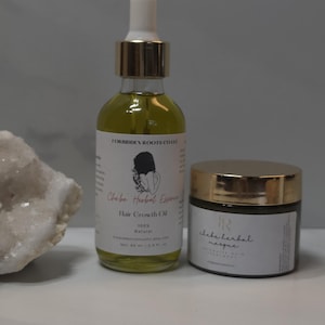May include: A clear glass dropper bottle of Chebe Herbal Essence Hair Growth Oil with a gold cap and a white label, alongside a small jar of Chebe Herbal Masque with a gold lid and white label, both featuring black text and branding.