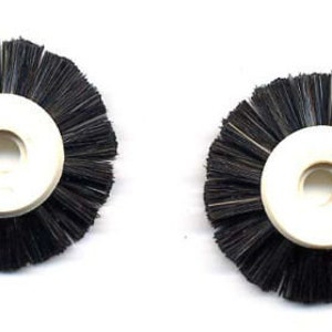 May include: Two black bristle brushes with white plastic centers. The brushes are circular and have a hole in the center.