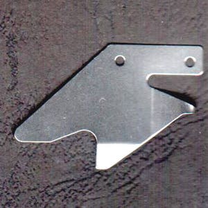 Könnte beinhalten: Ein silbernes Metallstück mit zwei Löchern und einer ausgeschnittenen Form. Das Stück ist dazu bestimmt, als Werkzeug oder als Teil eines größeren Objekts verwendet zu werden.