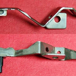 May include: Two metal sewing machine parts. The top part is a silver metal hook with a curved shape. The bottom part is a silver metal hook with a straight shape and a small metal pin.