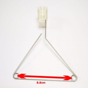 May include: A silver metal triangle with rounded ends and a white plastic piece at the top. The triangle measures 8.8 inches across.