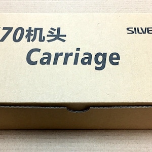 May include: A rectangular cardboard box with the text "SRJ70 Carriage" in dark gray and the brand name "SILVER REED" in black. The box is light brown and appears to be new.