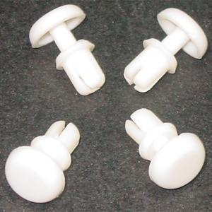 Puede incluir: Cuatro sujetadores de presión de plástico blanco con cabeza redonda y pasador partido. Estos sujetadores se utilizan comúnmente para sujetar paneles o molduras.