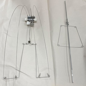 May include: A set of two silver metal bird feeders. The first feeder has a circular base with four curved wires extending upwards. The second feeder is a single straight wire with a rectangular frame at the top.