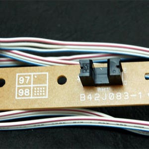 May include: A brown circuit board with a black sensor and a white wire with a connector. The board has the text "B42J083-1" and "GDV-0" printed on it.
