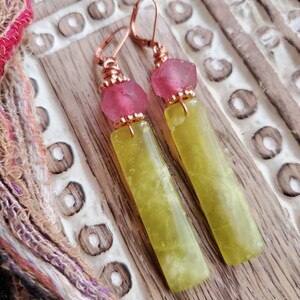 May include: A pair of dangle earrings with copper wire wrapped around green and yellow jade stone and pink glass beads.