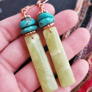 May include: A pair of dangle earrings with green jade stone and turquoise beads. The earrings have a copper wire design.