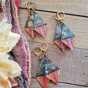 May include: Three pairs of handmade earrings. Each earring features a triangular shape with a gold-colored hoop. The top portion has a textured, blue-green patina, while the bottom is beaded in shades of pink, orange, and yellow.