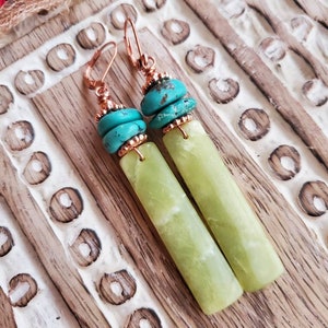May include: A pair of dangle earrings with green jade stone and turquoise beads. The earrings have copper wire accents and are suspended from copper hooks.