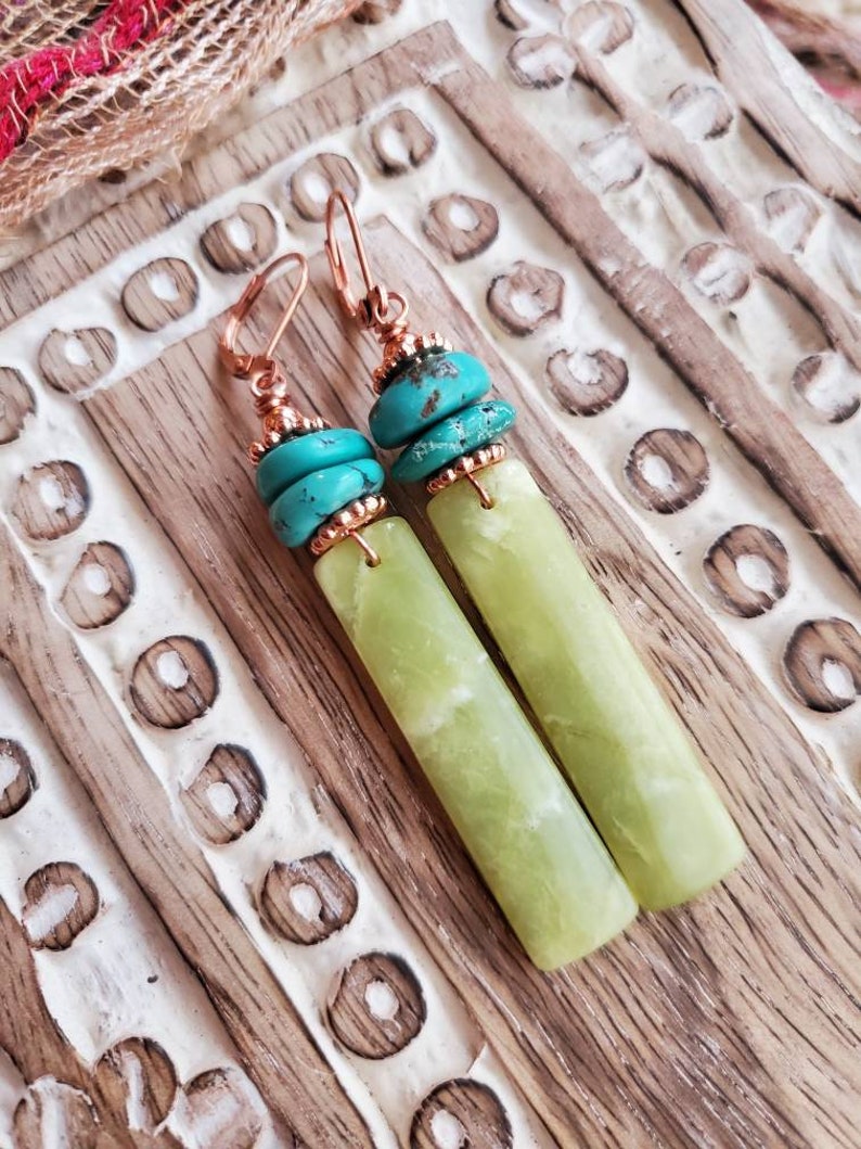 May include: A pair of dangle earrings with green jade stone and turquoise beads. The earrings have copper wire accents and are suspended from copper hooks.
