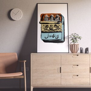 May include: A framed illustration of a blue and yellow can of sardines with three fish inside. The can has the word "Sardines" written on it in black cursive. The illustration is on a white background.