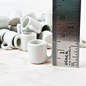 Multiple white miniature ceramic mugs grouped together on clean background