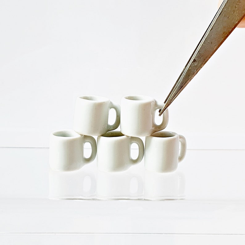 Multiple white miniature ceramic mugs grouped together on clean background
