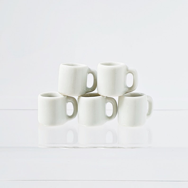 Bulk white ceramic miniature mugs piled together for quantity option display