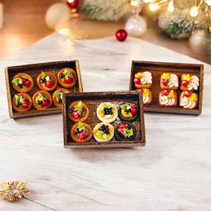 Puede incluir: Tres bandejas de madera llenas de postres en miniatura. Las bandejas están dispuestas en fila sobre una superficie de madera clara. Los postres están decorados con fruta, chocolate y otros ingredientes.