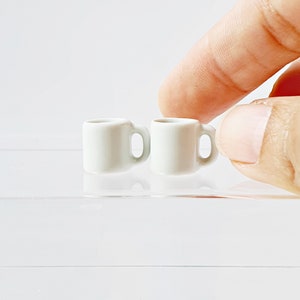Bulk white ceramic miniature mugs piled together for quantity option display