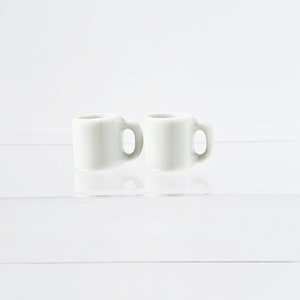 Bulk white ceramic miniature mugs piled together for quantity option display