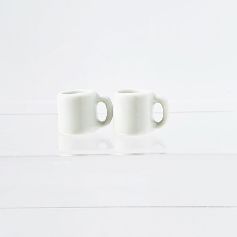 Bulk white ceramic miniature mugs piled together for quantity option display