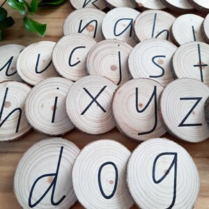 May include: Wooden alphabet letter tiles with black lettering. The letters are arranged in a random pattern, including the letters d, o, and g.