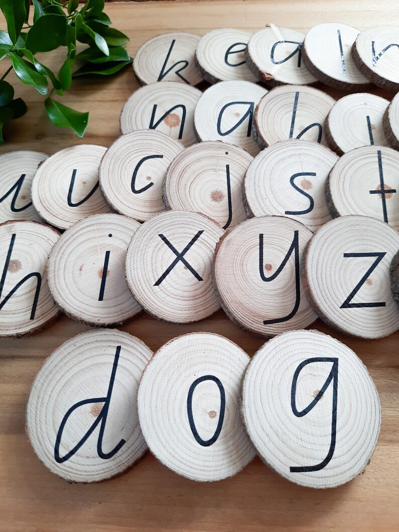May include: Wooden alphabet letter tiles with black lettering. The letters are arranged in a random pattern, including the letters d, o, and g.