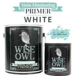 May include: Two black paint cans with the text "Stain Eliminating Primer White" and "Wise Owl" in white. The cans feature an illustration of an owl wearing a hat. The smaller can is next to the larger can.